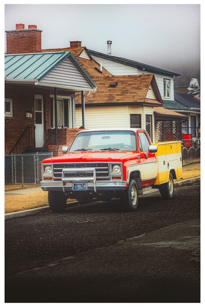 Vintage red and white pickup truck with yellow utility bed.